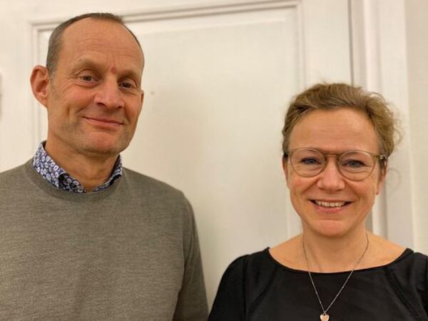 Två medarbetare poserar leende i en kontorsmiljö, vilket speglar GBJ Byggs professionella och engagerade arbetskultur där samarbetet mellan teamen är en central del av verksamheten.