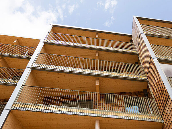 En fasad med träbalkonger och naturliga materialval visar GBJ Byggs arbete med arkitektur som fokuserar på värme, detaljrikedom och hållbara bostadslösningar.