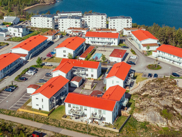 Flygbild över hela bostadsområdet visar en tydlig struktur av vita trähus med röda tak, där GBJ Bygg skapat ett sammanhängande och naturnära kvarter med utsikt över Uddevallas kustlinje.