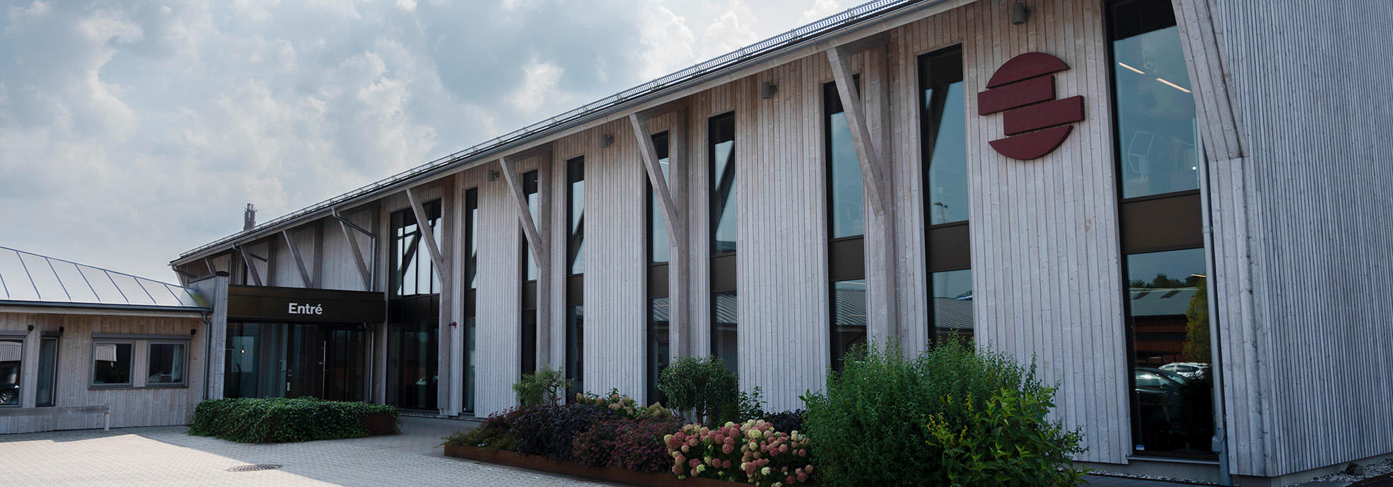 En lång fasad med träpanel och stora skyltfönster visar GBJ Byggs arbete med att skapa moderna lokaler där handel och samhällsservice integreras i bostadsområden.