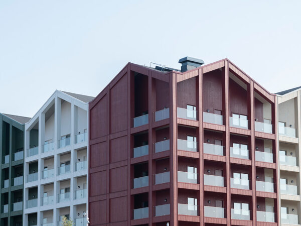 Ett sammanhängande flerbostadsområde med färgstarka fasader och strukturerade balkonglinjer framträder; GBJ Byggs arbete ger området en modern identitet med välplanerad volym och arkitektonisk variation.