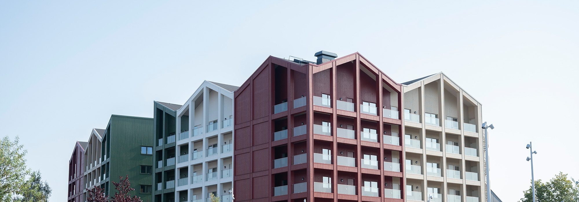 Ett sammanhängande flerbostadsområde med färgstarka fasader och strukturerade balkonglinjer framträder; GBJ Byggs arbete ger området en modern identitet med välplanerad volym och arkitektonisk variation.