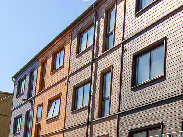 En lång fasad med fönster och träpanel illustrerar GBJ Byggs precisa materialval för att ge Kungsängen en modern, hållbar och harmonisk arkitektonisk identitet.