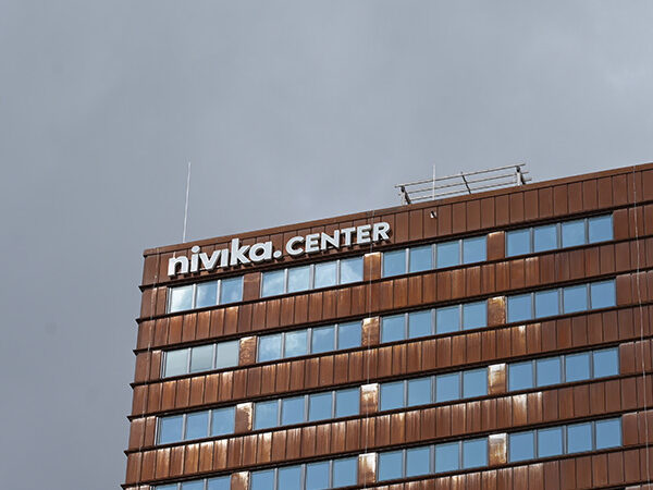 Ett högt hus med distinkt vertikal arkitektur sträcker sig mot himlen, och GBJ Byggs tekniska kompetens framträder i byggnadens komplexa trädesign.