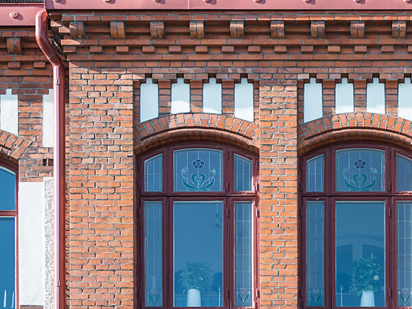 Detaljerad fasad i rött tegel med dekorativa mönster och välvda fönster visar den kulturhistoriska karaktären i kvarteret Argus, där GBJ Bygg varsamt renoverat byggnaderna för att bevara uttrycket samtidigt som funktion och hållbarhet moderniserats.