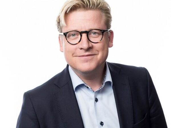 Ett professionellt porträtt av en representant från GBJ Bygg, klädd i kostym och skjorta, där den rena vita bakgrunden framhäver företagets affärsmässiga profil och ledarskap.