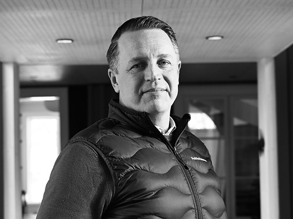 Ett porträtt av en verksamhetsutvecklingschef inom byggbranschen, fotograferad inomhus i en modern kontorsmiljö. Personen bär väst och står avslappnat. Bilden, personal-morgan-gård.jpg, speglar GBJ Byggs fokus på ledarskap, utveckling och långsiktigt företagande.