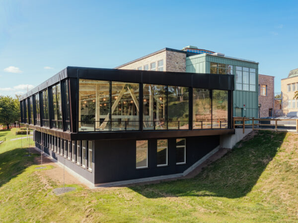 En modern tillbyggnad på Västerhöjdsgymnasiet med svart fasad och stora glaspartier ansluter till den befintliga tegelbyggnaden. GBJ bygg har skapat en arkitektonisk kontrast där synlig trästomme och generöst dagsljus präglar skolmiljön.