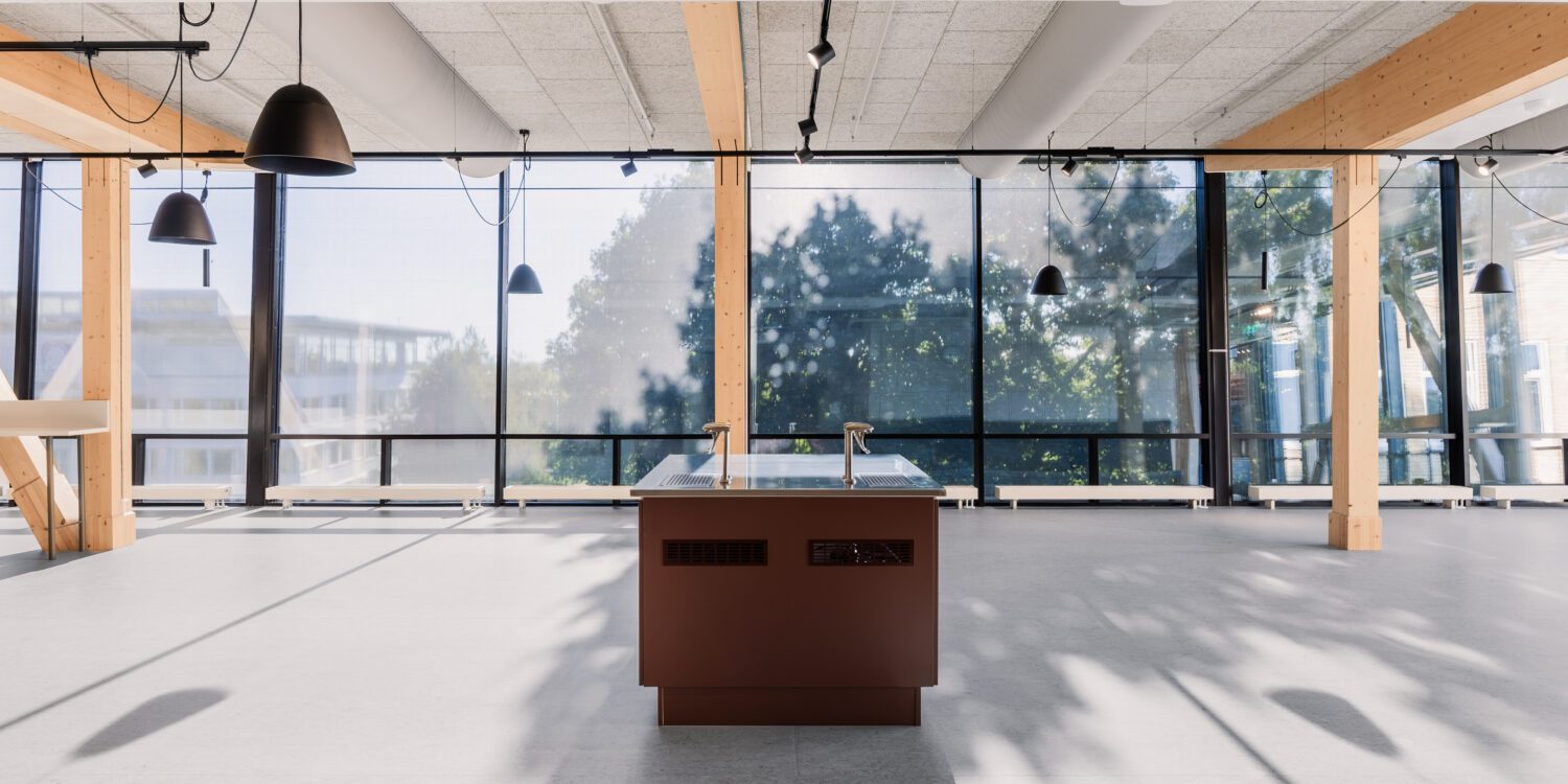 En ljus och öppen skolmiljö med stora glaspartier, synliga träpelare och en central arbetsstation. GBJ bygg har skapat en flexibel yta där naturligt ljus och trädetaljer bidrar till en trivsam studiemiljö.